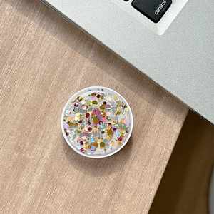 Detail view of round glitter phone socket with sequins on a light wood desk setup