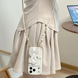Close-up of beige leather iPhone case with bow strap and pearl crossbody chain