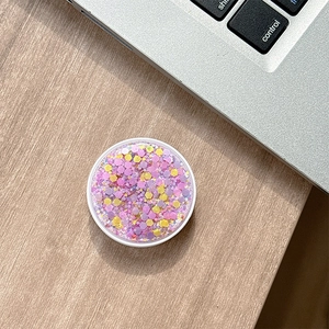 Detailed close-up of a round phone grip featuring sparkling colorful hexagonal glitter