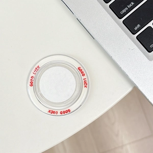 Macro view of a round transparent magnetic phone socket with red Good Luck text on a desk