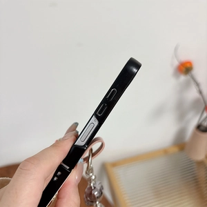 Détail de la coque noire mate avec découpes de boutons et lanière en cuir rose