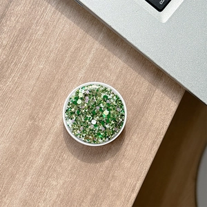 Close-up of a round green glitter phone socket on a light wooden desk setup