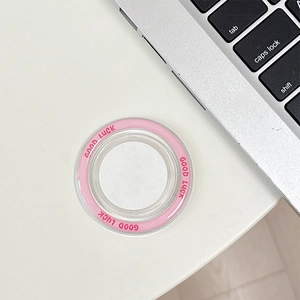 Pink circular MagSafe phone stand with Good Luck text shown next to a laptop