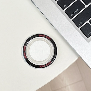 Detail of DIY magnetic phone grip with Good Luck text on a clean desktop with laptop
