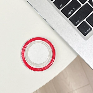 Top view of circular magnetic phone grip with red Good Luck text on a white desk