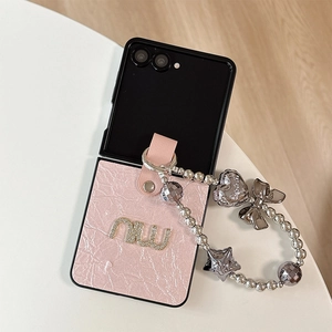 Détail de la coque en cuir plissé rose avec lettres dorées et breloque perlée