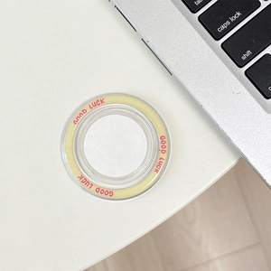 Macro view of clear circular phone grip with Good Luck slogan on a white desktop