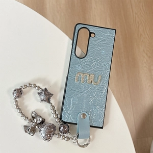 Détail d'une coque en cuir bleu clair avec lettres en strass et dragonne étoile élégante