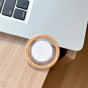 Detail of a round Gift For You magnetic phone grip sticker on a wooden office desk