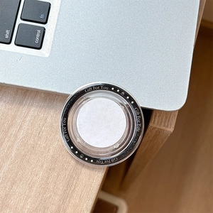 Detail of round MagSafe phone socket with 'Gift For You' text on minimalist wooden desk