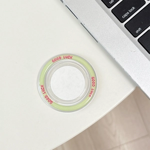 Macro view of transparent round phone grip with green ring and pink Good Luck text