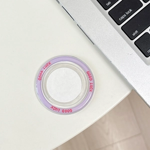 Detail of a purple Good Luck magnetic phone grip stand on a white desktop background