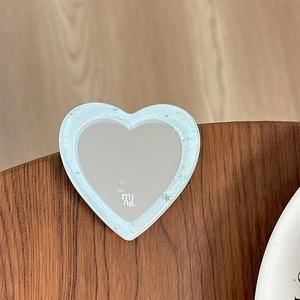 Detail of blue glitter heart shaped mirror phone grip with mine text on wooden surface