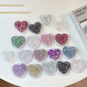 Glitter heart-shaped popsocket phone stands in various colors on a white table
