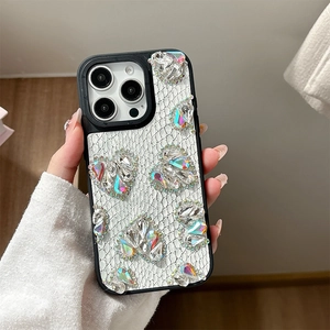 Detailed view of white snakeskin texture and rhinestone heart charms on iPhone case