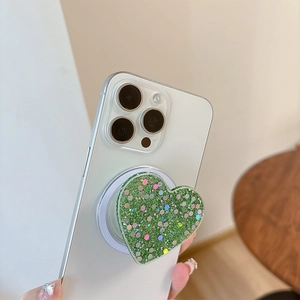 Detailed macro of heart-shaped phone grip with glittery green sequins on white smartphone
