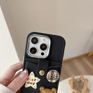 Detail der schwarzen iPhone-Tasche mit Karomuster, cremefarbenem Stern und 3D-Bärenanhänger