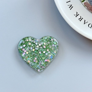 Detail of heart-shaped phone grip with green glitter and sparkling resin sequins