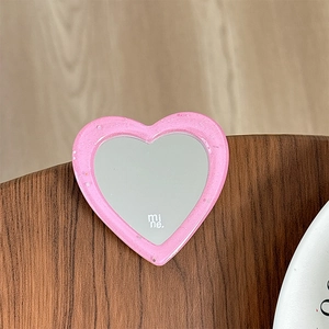 Detailed view of a pink glitter heart-shaped phone grip mirror with mi ne text branding
