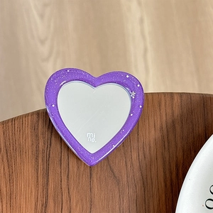 Macro shot of purple glitter heart-shaped phone grip mirror on dark wood surface