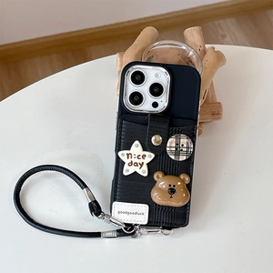 Detail der schwarzen iPhone-Hülle mit Kartenfach, Bärenanhänger und Stern-Patch