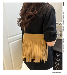 Detail of bohemian fringe crossbody bag in mustard yellow suede texture on model