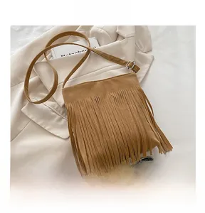 Detail of a brown matte suede bucket bag with long fringes and adjustable silver buckle