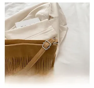 Close-up of brown suede tassel bag detail featuring a square silver metal buckle