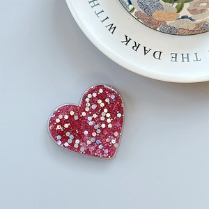 Macro shot of red heart-shaped phone grip with glitter and holographic sequins