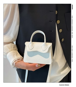 Détail du mini sac à main blanc avec rabat ondulé et texture cuir de litchi