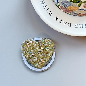 Close-up of heart-shaped phone grip with golden sequins and glitter finish