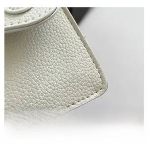 Gros plan sur la texture du cuir litchi blanc et les coutures précises du sac à main
