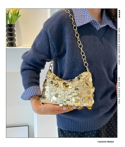 Close-up of sparkling gold sequin crescent bag with thick metal chain strap details