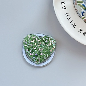 Macro view of green glitter heart phone grip with folding stand and sparkling finish