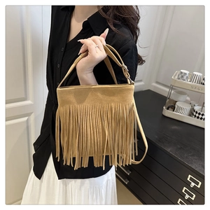 Detailed view of camel suede handbag with long fringe tassels and adjustable strap