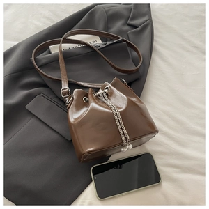 Detail der dunkelbraunen Leder-Eimertasche mit Silberketten, Perlen und Handy-Größenvergleich