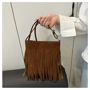 Detail of brown suede tote bag featuring long fringes and adjustable thin handle straps