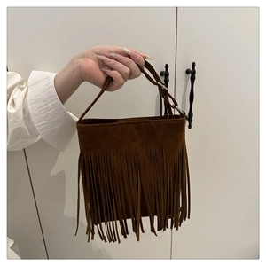 Detail of brown suede handbag featuring long tassel fringes and adjustable handle