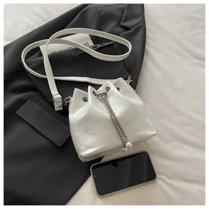 Detail der weißen Beuteltasche mit Kordelzug, Metallkette und Perlenanhängern