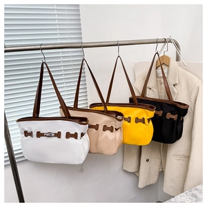 Détail de quatre grands sacs cabas en nylon blanc, beige, jaune et noir avec anses en cuir