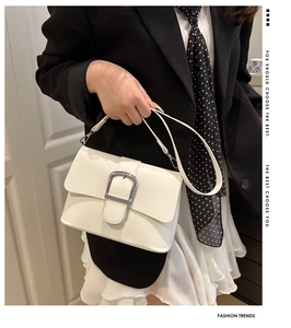 Close-up of white leather handbag featuring a stylish silver U-shaped metal buckle detail
