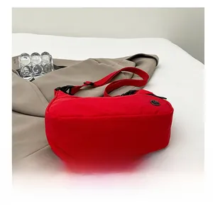Detail view of the durable rectangular base of a red nylon crossbody dumpling bag