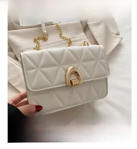 Détail d'un sac blanc matelassé avec fermoir doré et bandoulière chaîne sur un costume