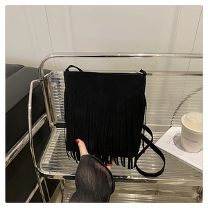 Close-up of black fringe detail on a stylish suede shoulder bag with thin strap