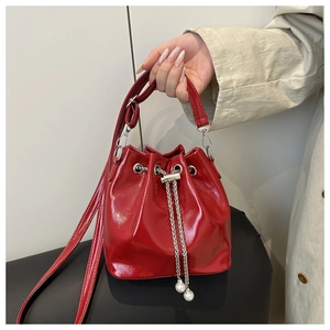 Detail der roten glänzenden Beuteltasche mit Kordelzug, Silberkette und Perlenanhängern