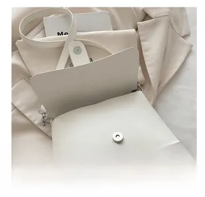 Close-up of minimalist white shoulder bag with silver magnetic snap button closure