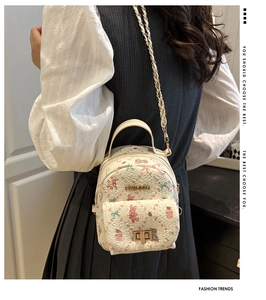 Close-up of white mini floral backpack with chain strap and gold fashion logo