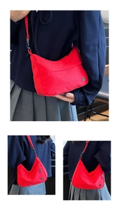 Detail of red nylon crescent crossbody bag with adjustable strap and metal logo