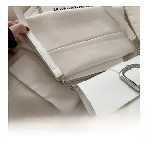 Detail of silver metallic hardware hook and stitching on white patent leather bag