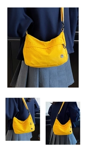 Detail of bright yellow nylon crossbody bag featuring a round metallic M logo and zipper